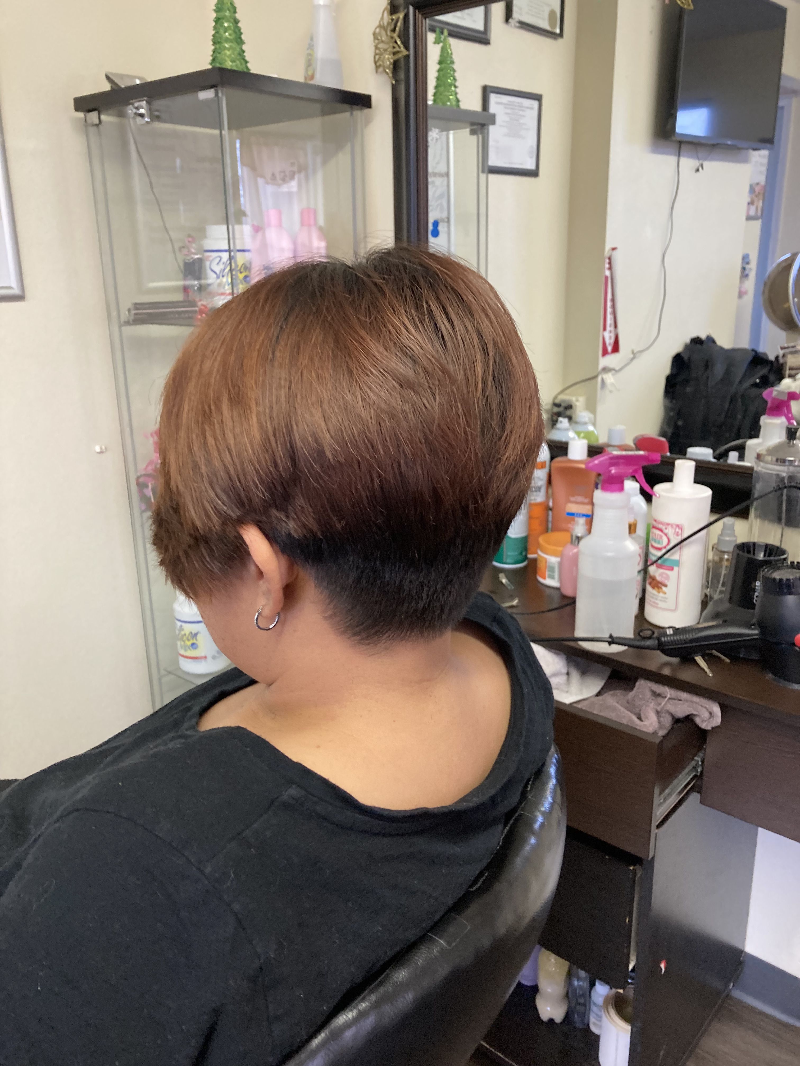 Woman with a short, bowl-cut hairstyle. The hair is layered, with the top section being longer and the bottom section closely shaved.