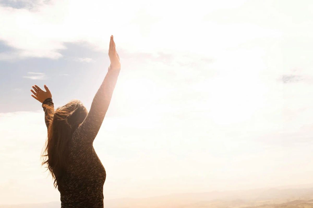 Frau streckt die Arme in den Himmel, Symbol für neue Freiheit und Leichtigkeit nach erfolgreicher Hypnosebehandlung.