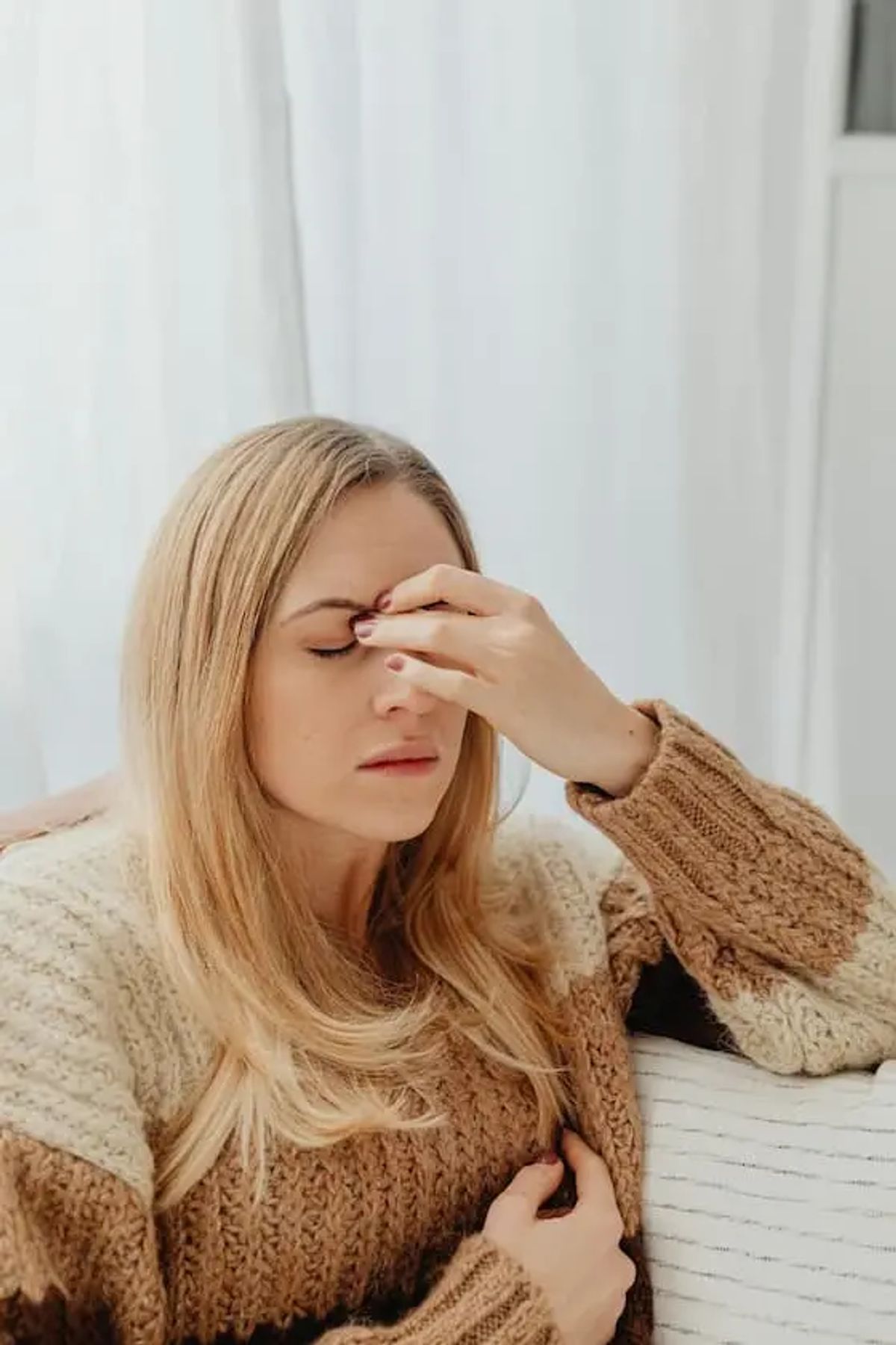 Junge Frau hält sich die Stirn vor Schmerzen, Darstellung einer Migräneattacke vor der Hypnosebehandlung.
