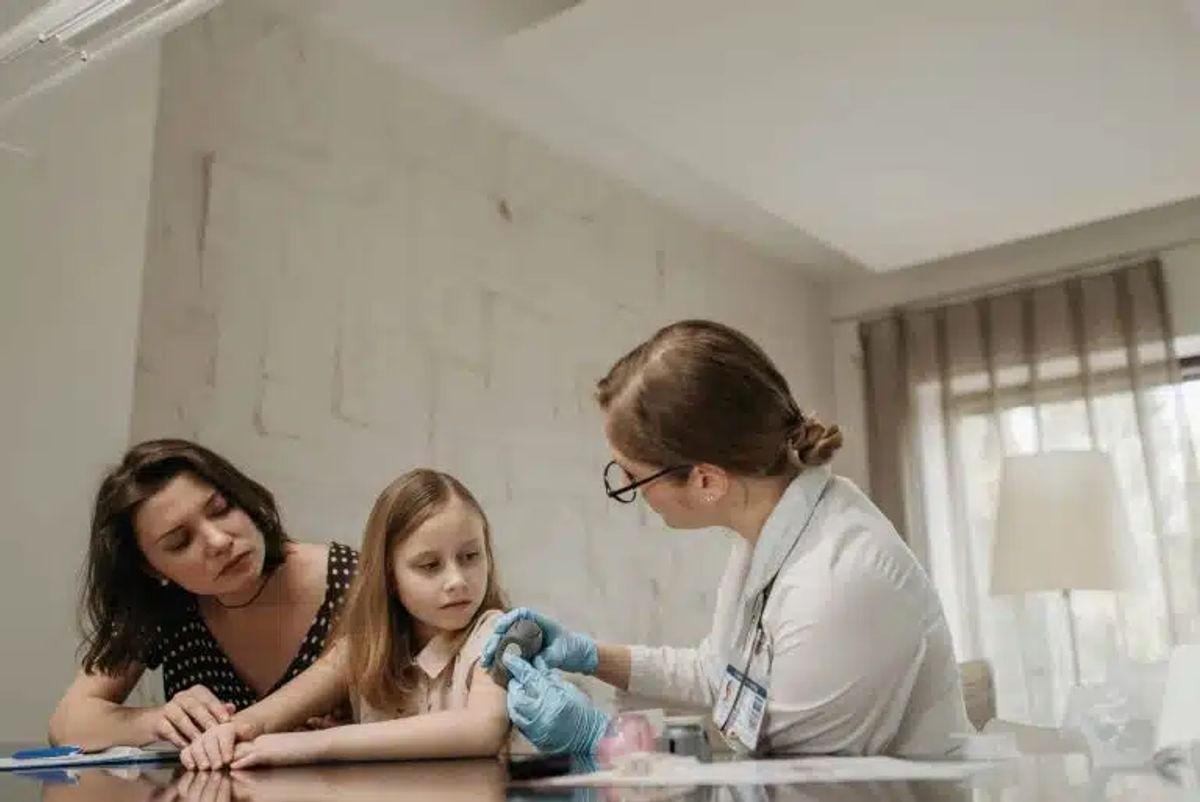 Ärztin beruhigt Mutter und Tochter vor einer Spritzenbehandlung