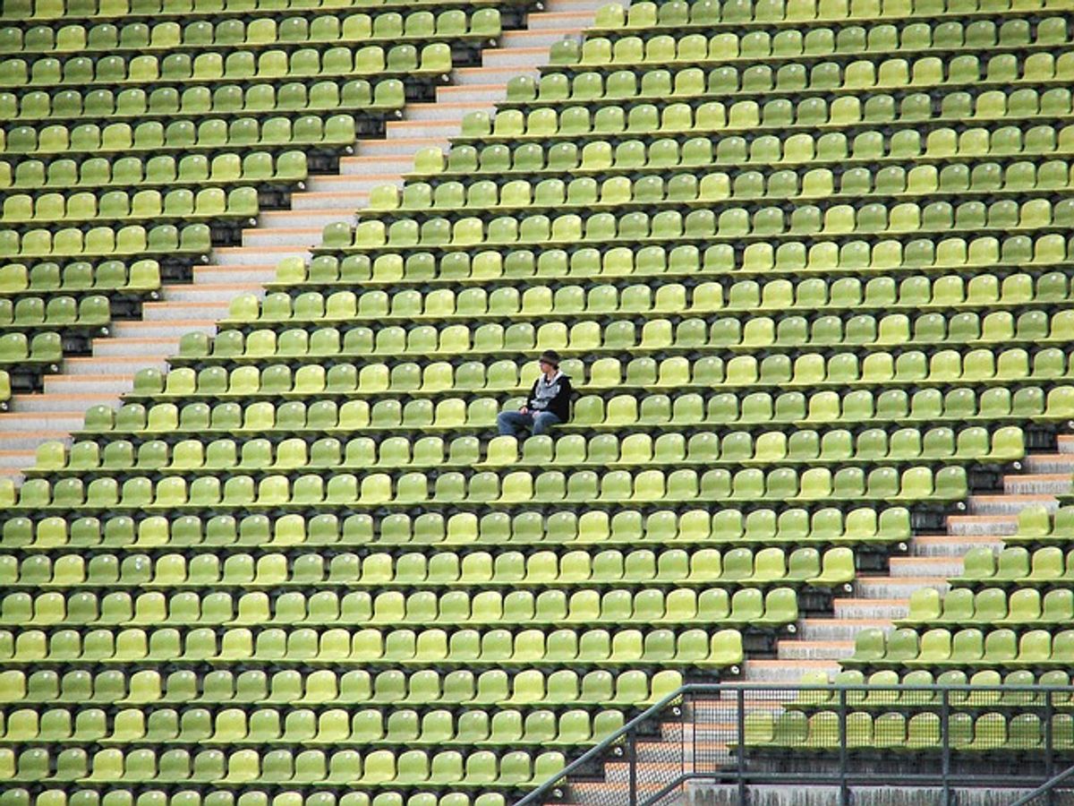 Person sitzt allein auf einer Tribüne, symbolisiert soziale Phobie und Einsamkeit