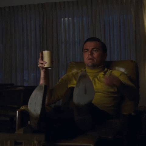 alt="Leonardo Dicaprio tenant une canette de bière dans une main et sautant pour montrer la télévision de l'autre main."