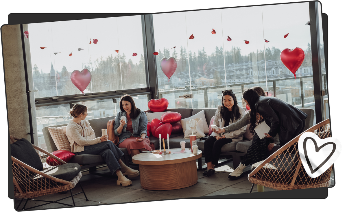 alt="Photo de cinq femmes dans un salon sur un canapé s'entraidant, entourées de ballons en forme de cœur."