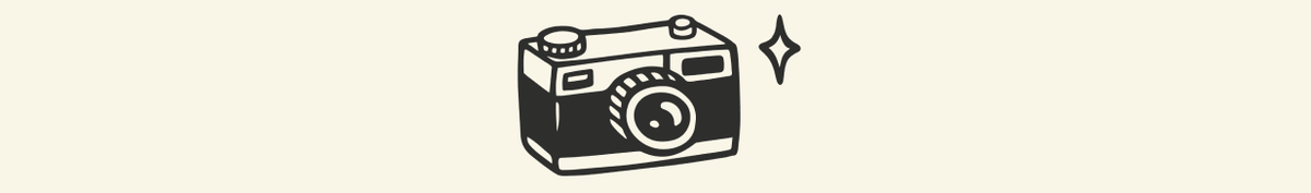 alt="Black and white cartoon drawing of a camera with a sparkle next to it"