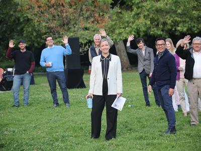 Pastoral staff and church members stand (socially distanced) in a park and wave to the camera.