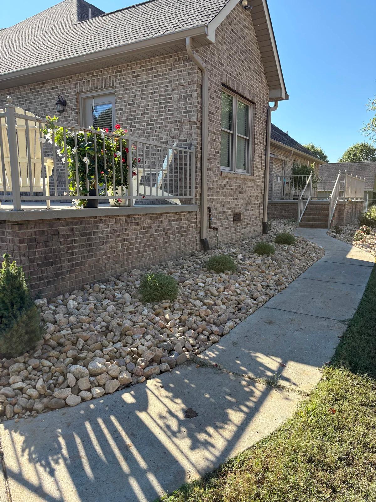 Side of home with rock hardscaping with plants in the middle