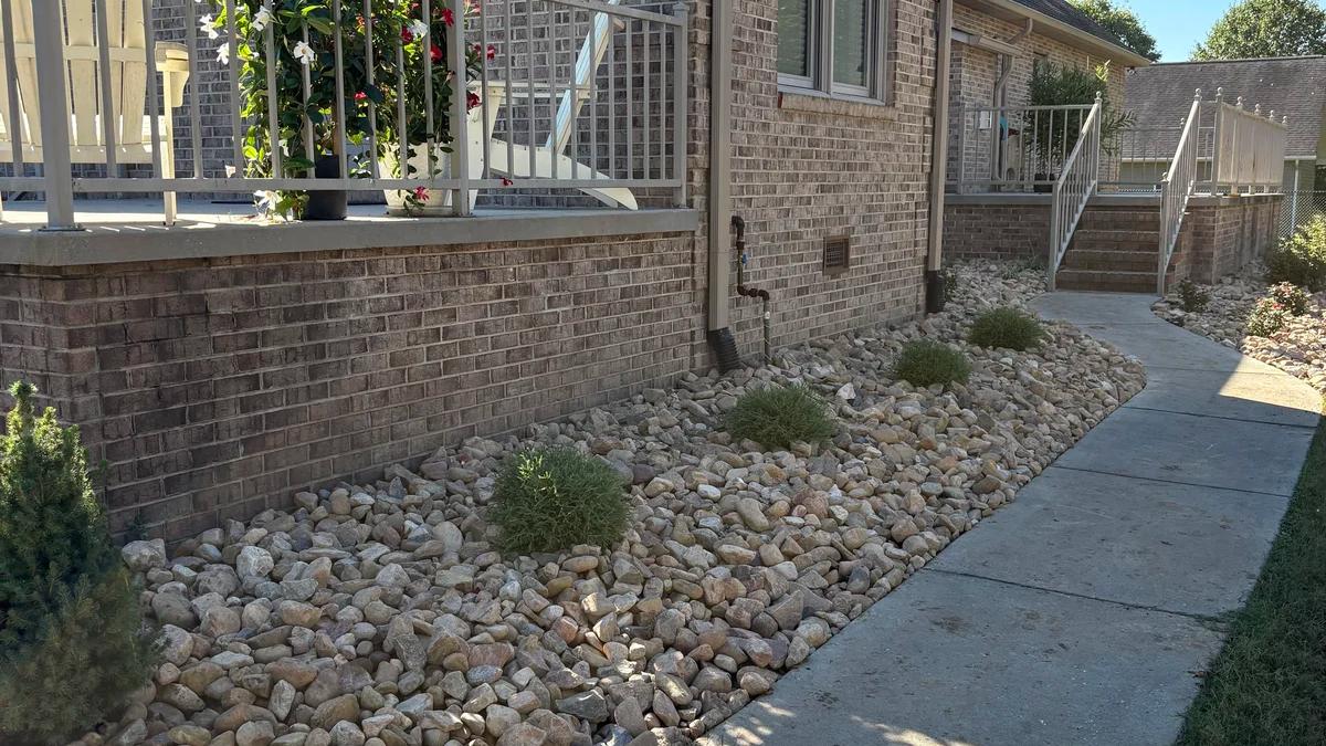 Side of home with rock hardscaping with plants in the middle
