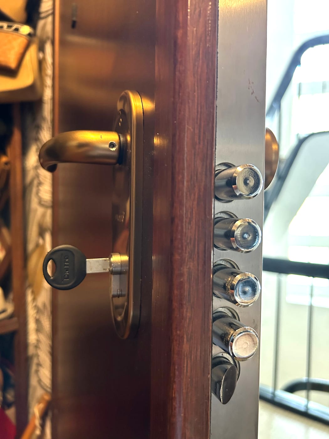 Edge of a wooden door with four cylindrical metal bolts extended, key in the lock