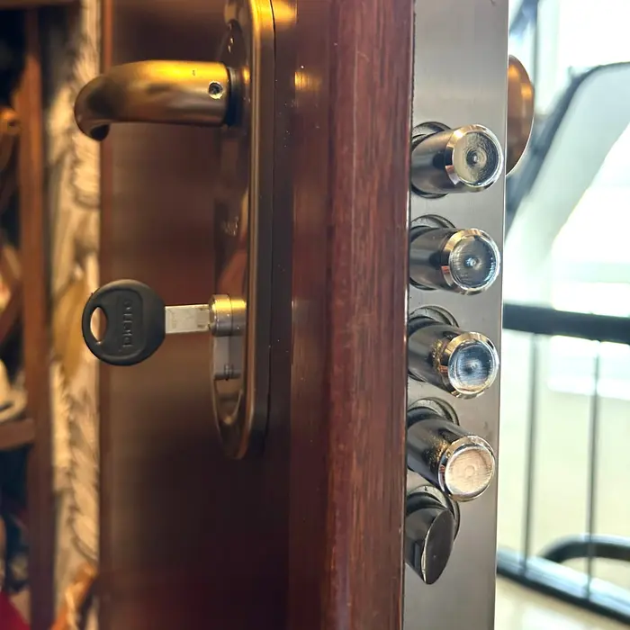 Edge of a wooden door with four cylindrical metal bolts extended, key in the lock