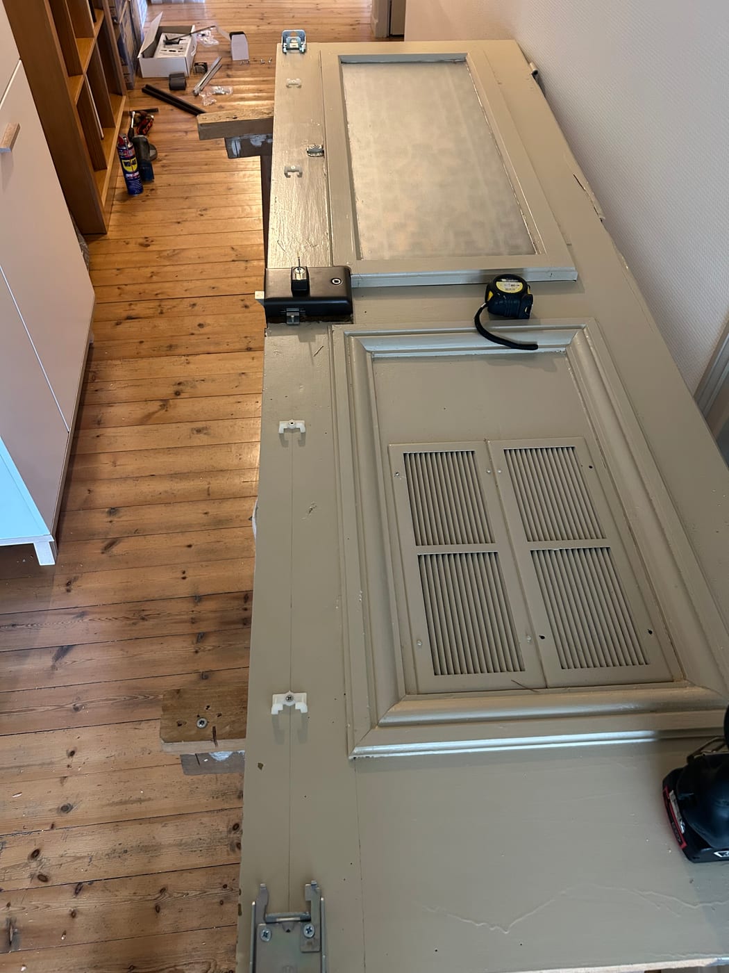 Beige door laid flat on trestles, a long metal bar fixed along its full height