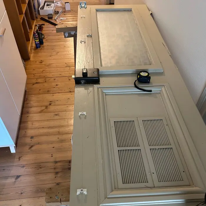 Beige door laid flat on trestles, a long metal bar fixed along its full height
