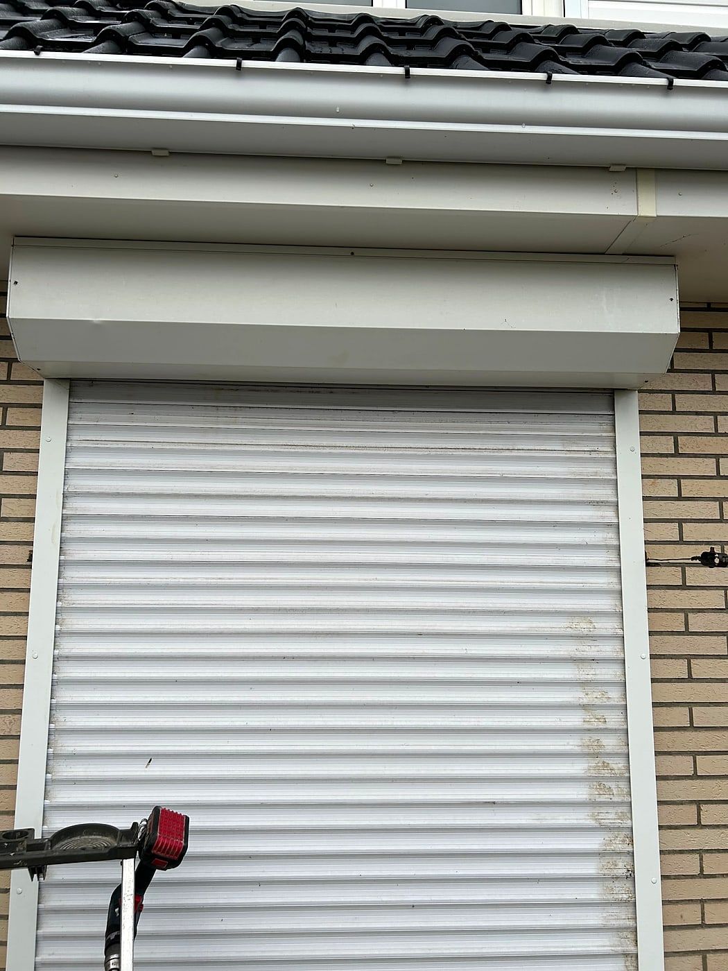 White roller shutter on a brick facade