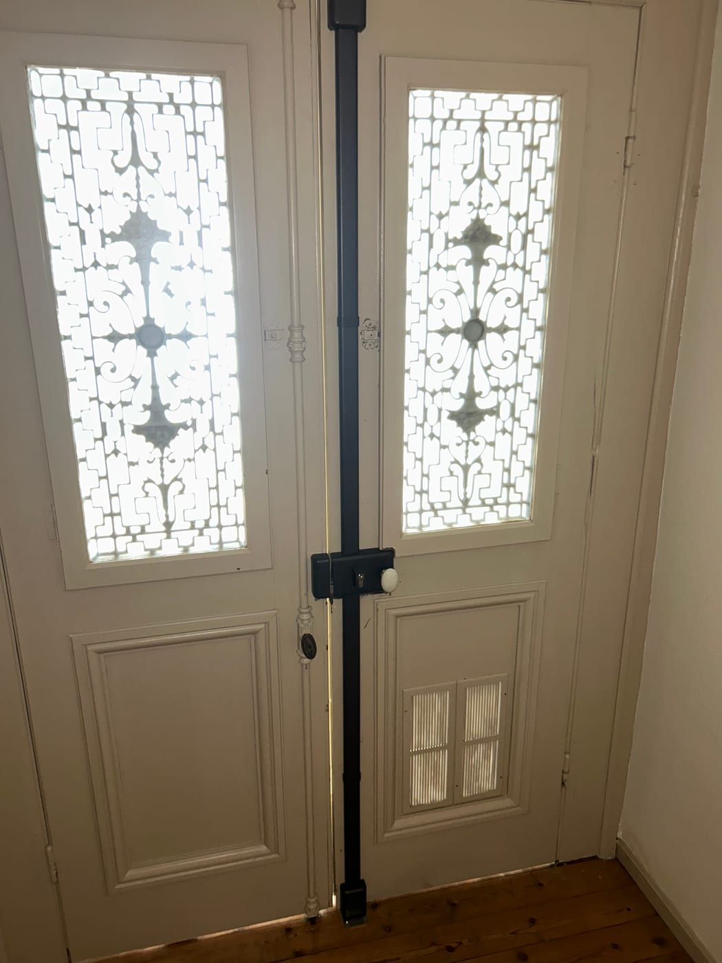 White double front door with leaded glass, a black metal bar fitted vertically down the centre