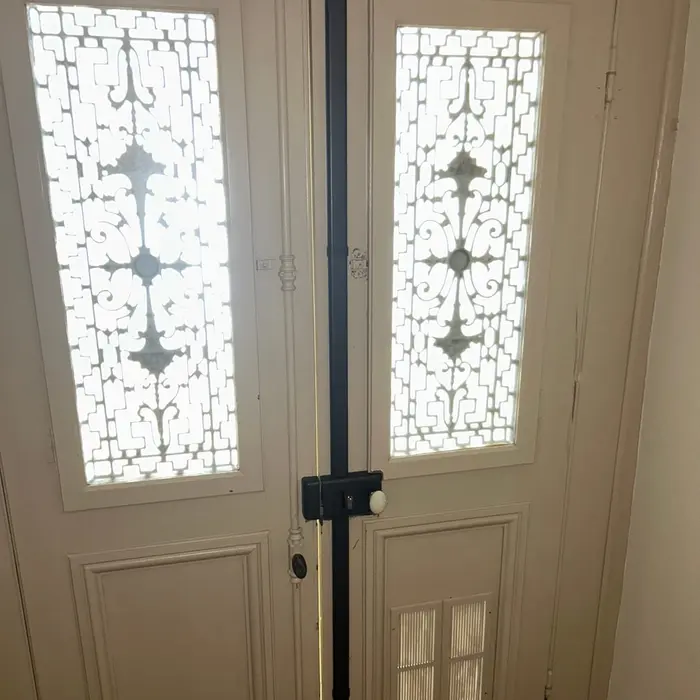 White double front door with leaded glass, a black metal bar fitted vertically down the centre