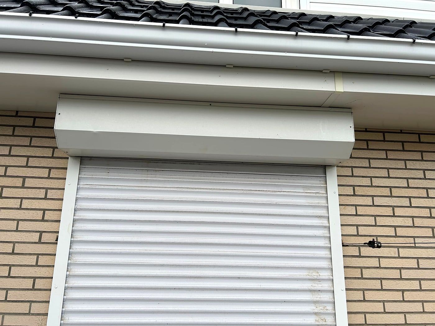 White roller shutter closed over a window