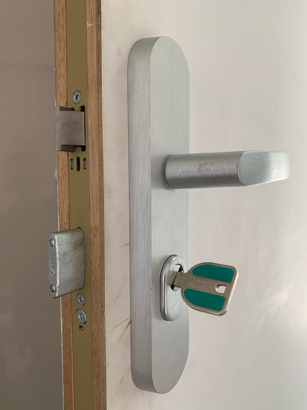 Aluminium handle and key on a white door, open edge visible