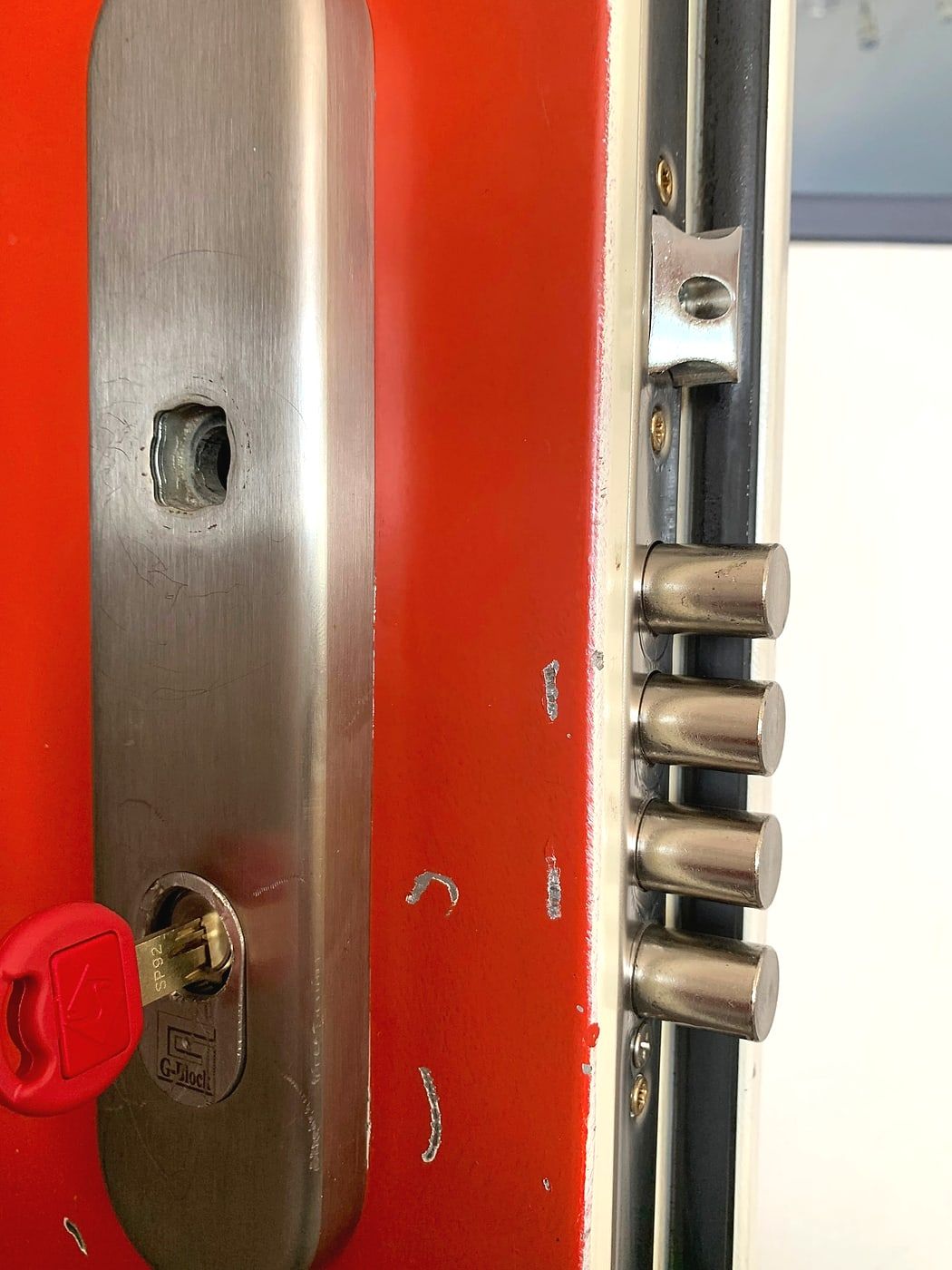 Open lock on a red door, metal rods visible