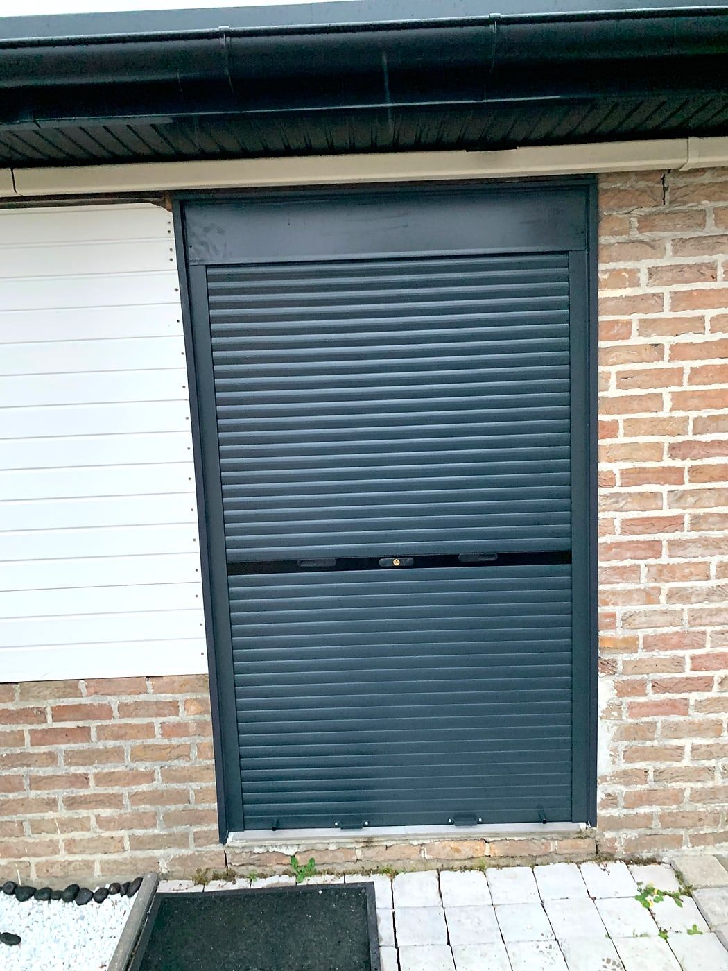 Dark grey roller shutter on a brick facade
