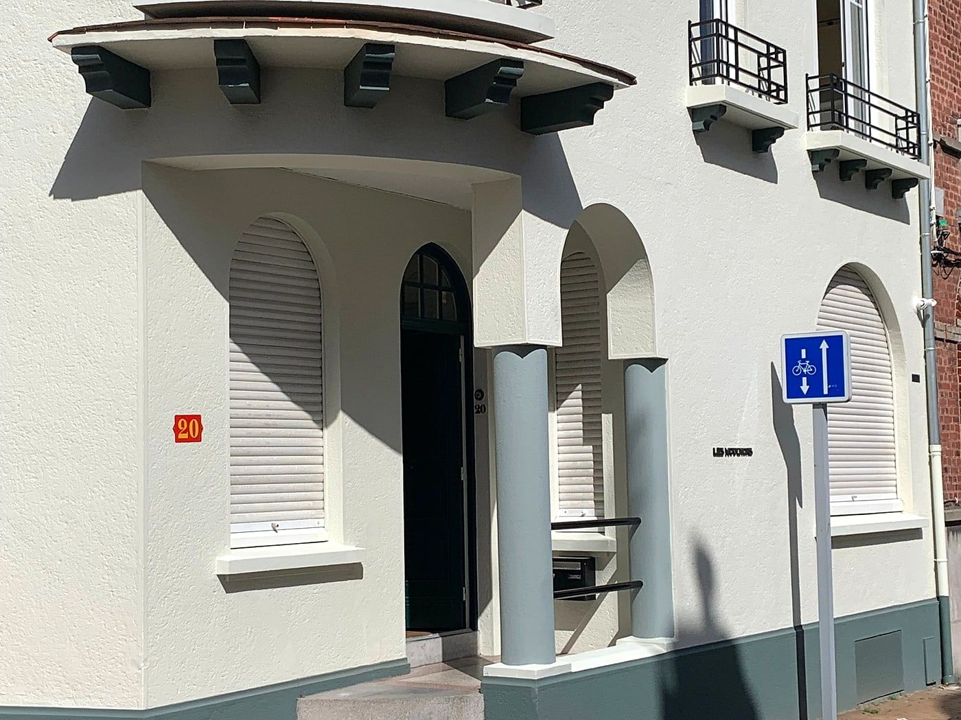Light facade with an arched front door and white shutters