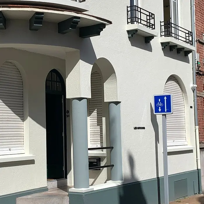 Light facade with an arched front door and white shutters