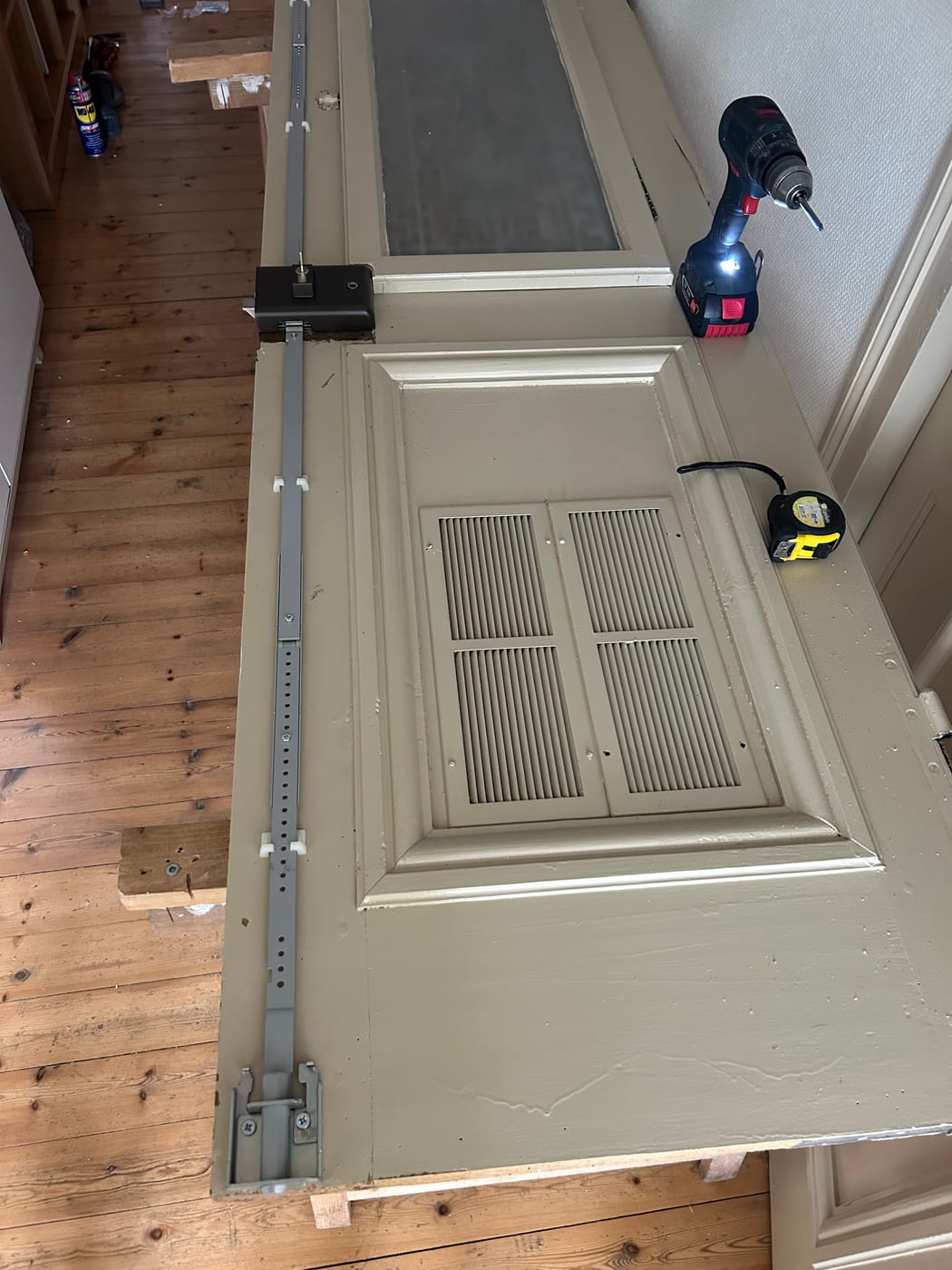 The same door being worked on, with a drill and tape measure alongside