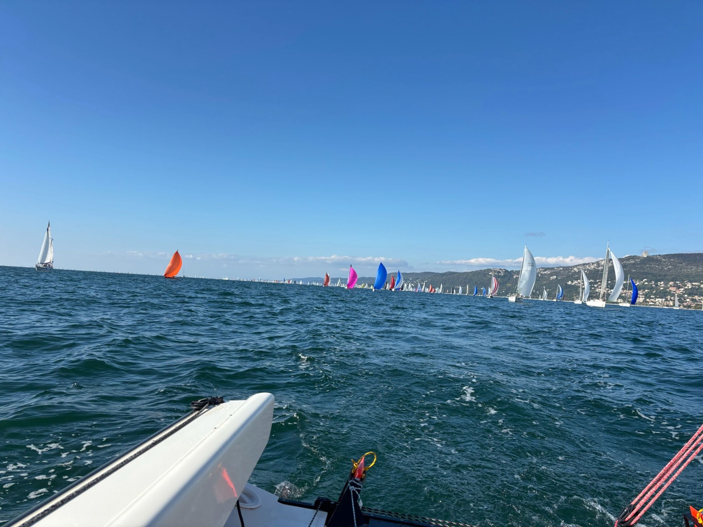 The bow in the Barcolana fleet, coloured spinnakers on the horizon
