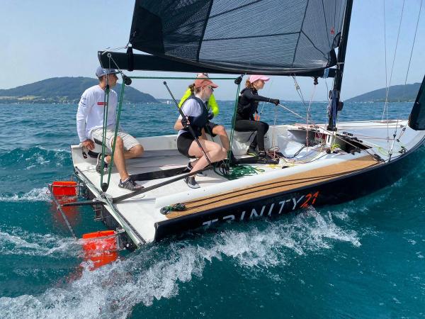 Eine Trinity 21 der Sailing Juniors am Wind, drei Jugendliche auf der Bordwand