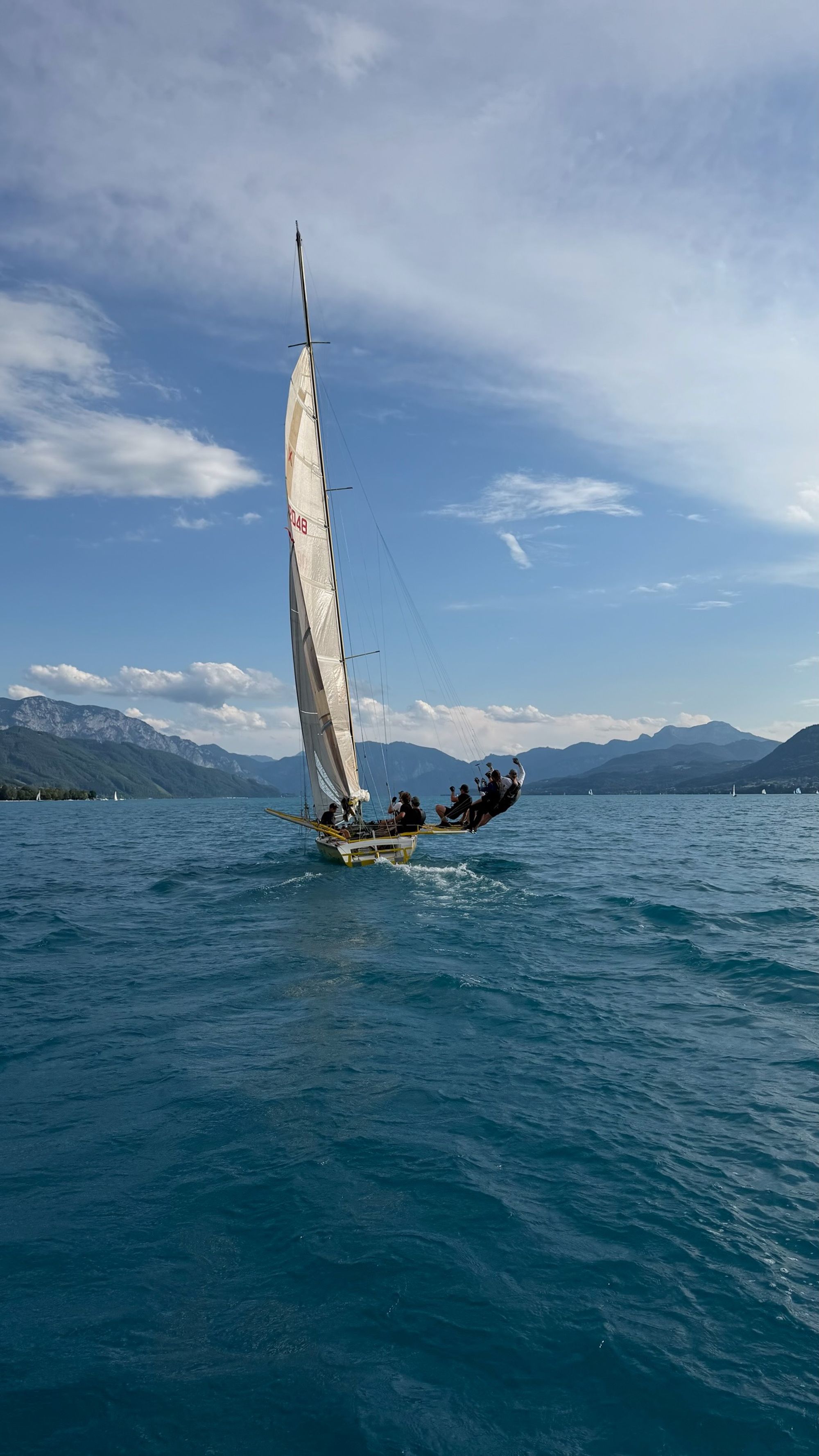 A racing yacht under full sail on Lake Attersee, clouded sky above