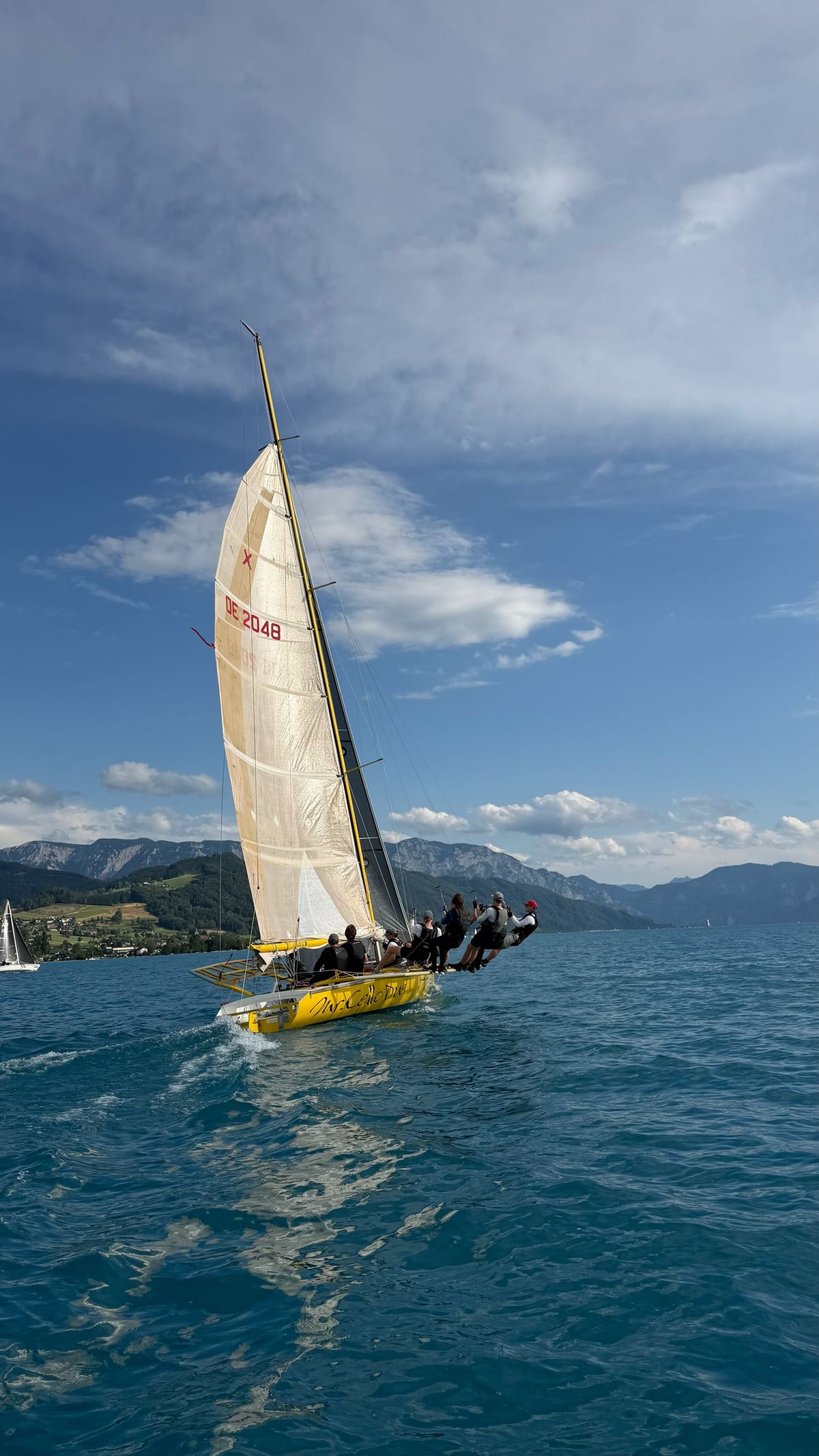 Mr. Cello Due sailing upwind against the mountains around Lake Attersee, crew hiking out