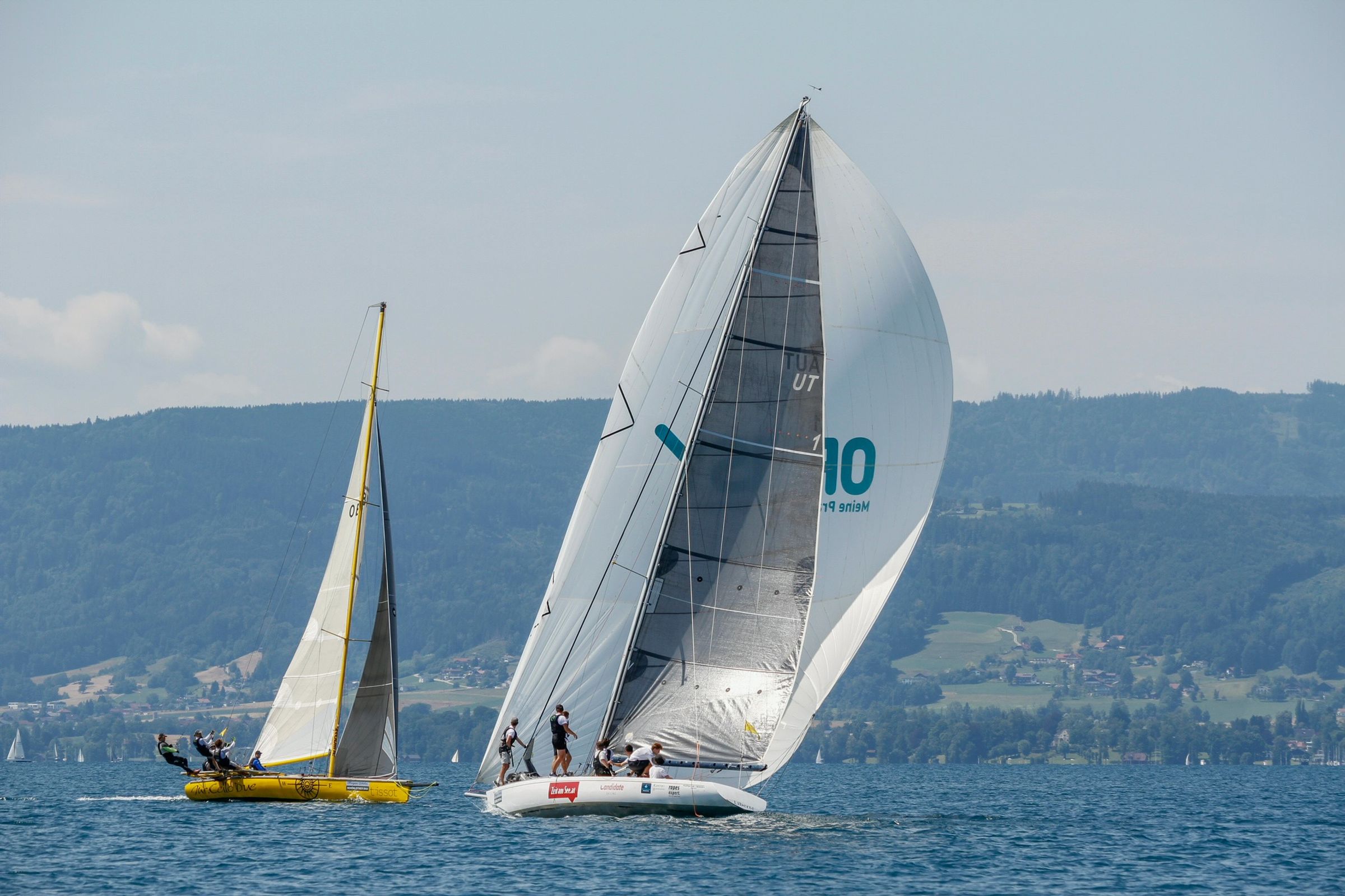 Both team boats in one shot, the yellow Mr. Cello Due behind a white yacht