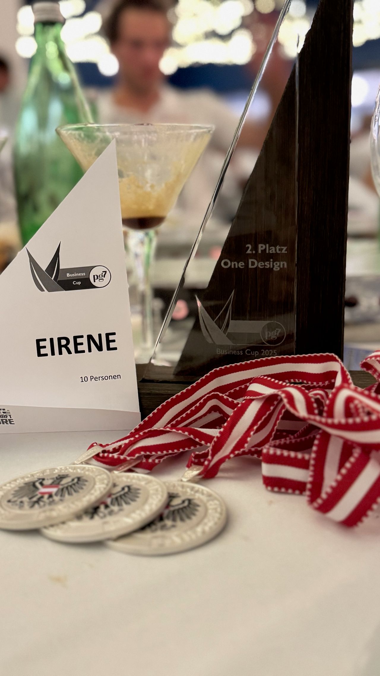 Three silver medals bearing the federal eagle beside the glass trophy for second place, Eirene’s table card in front