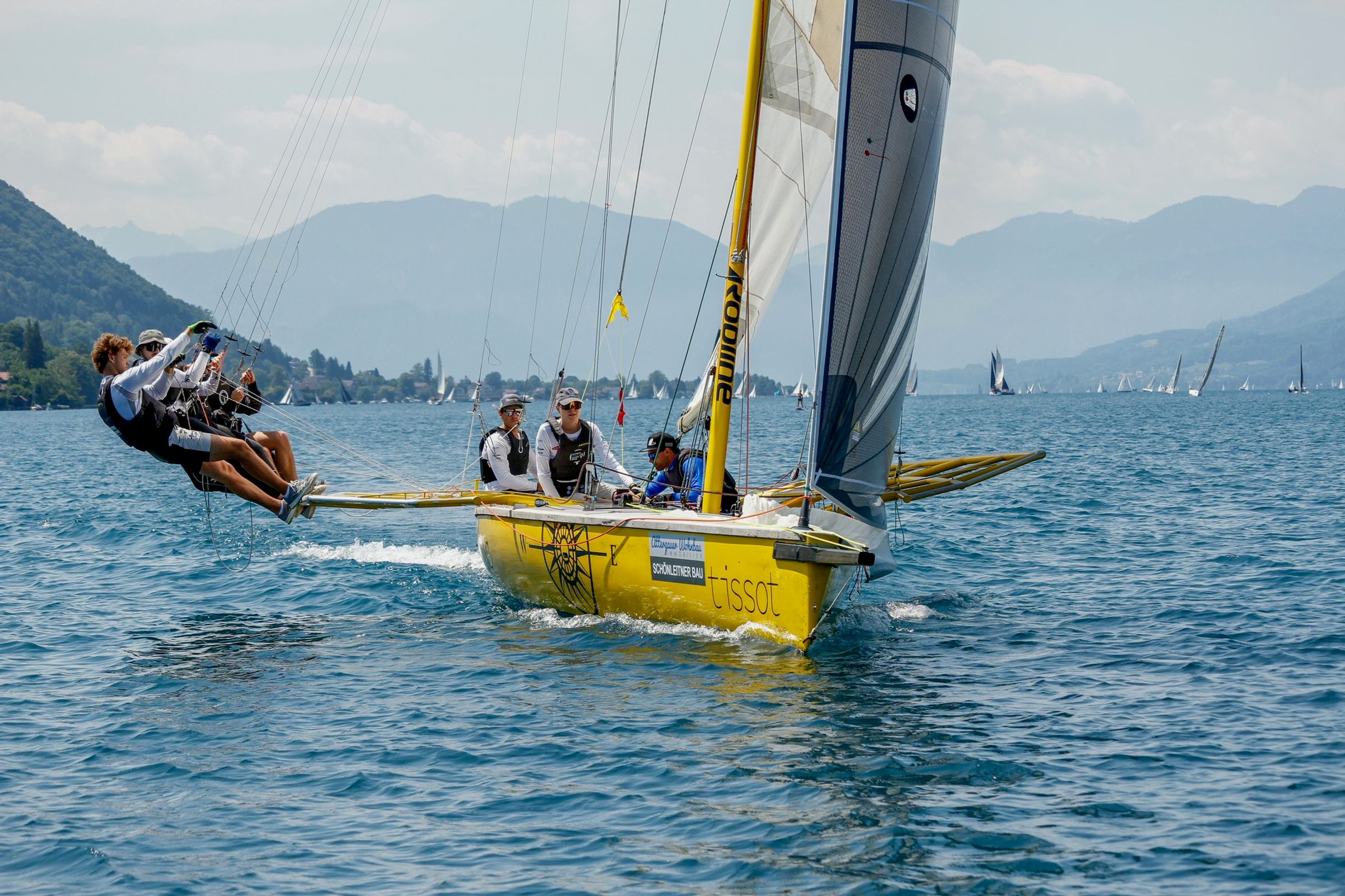 The yellow Mr. Cello Due under full sail, one crew member far out on the rail