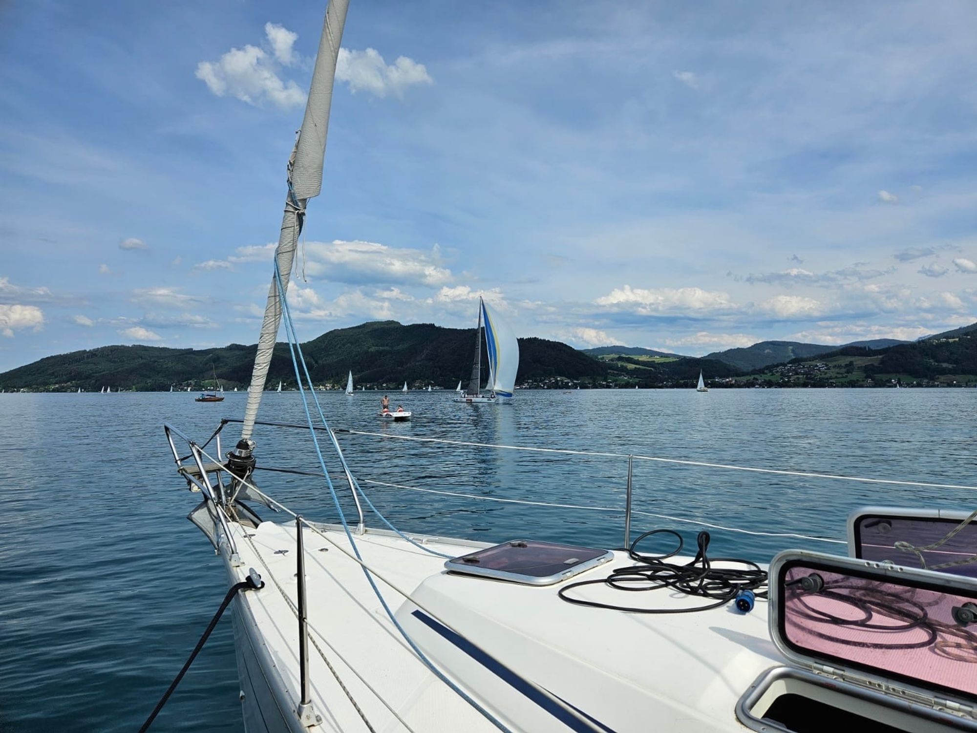 Blick vom Vorschiff über den Attersee, Segler in der Ferne vor der Bergkette