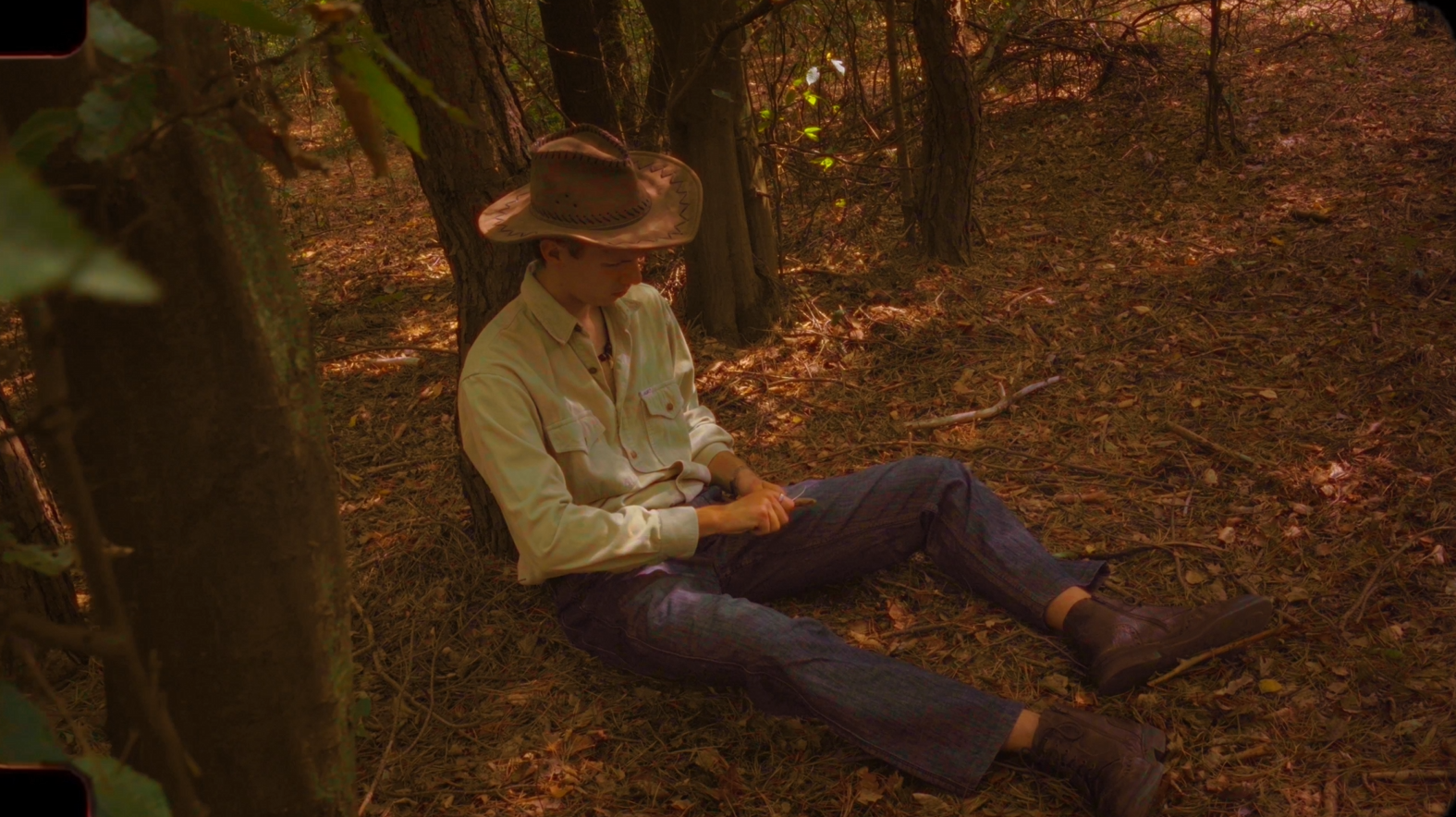 A young explorer rests beneath a tree in the warm afternoon light.