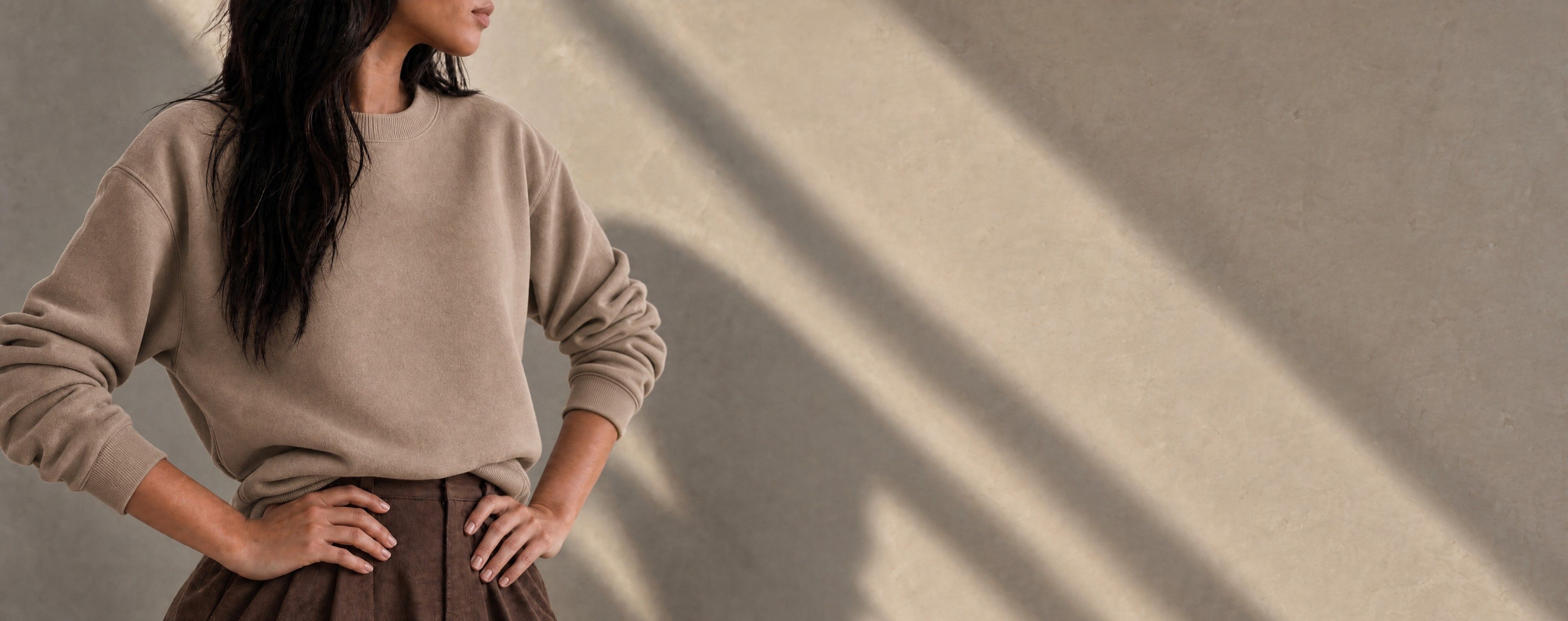 Woman in a sweatshirt standing with her hands on her hips in warm light