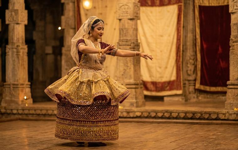 Manipuri classical dancer in a decorated barrel-shaped kumil skirt and veil performing a graceful pose