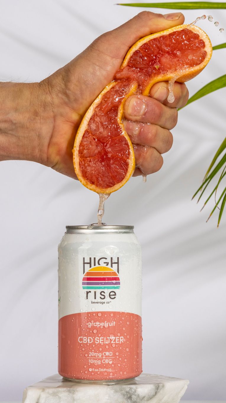 grapefruit cbd seltzer with a fresh grapefruit being squeeze in