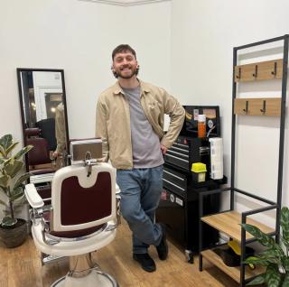 Robin in the shop, standing beside the vintage barber chair