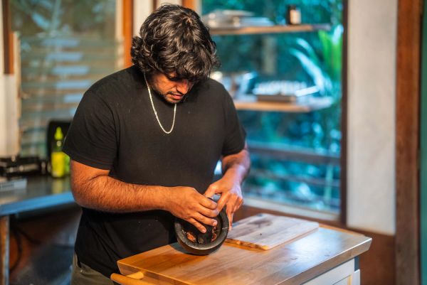 Chef Yuda Abitbol working with a mortar and pestle in the kitchen.