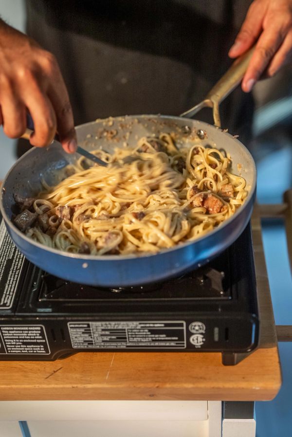 Close-up of pasta being tossed in a pan.