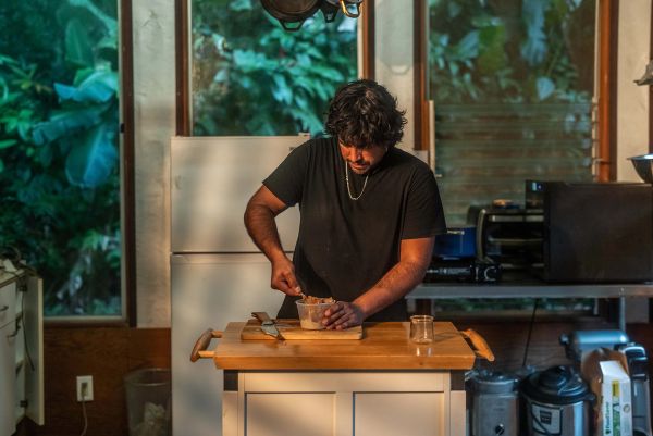 Chef Yuda Abitbol preparing ingredients at a wooden kitchen counter.