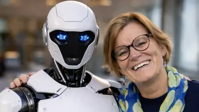 Kirsti Kierulf og den humanoide roboten NEO. Bildet er KI generert av Sindre Haarr, basert på foto av Kirsti tatt av Chris Caspersen.
