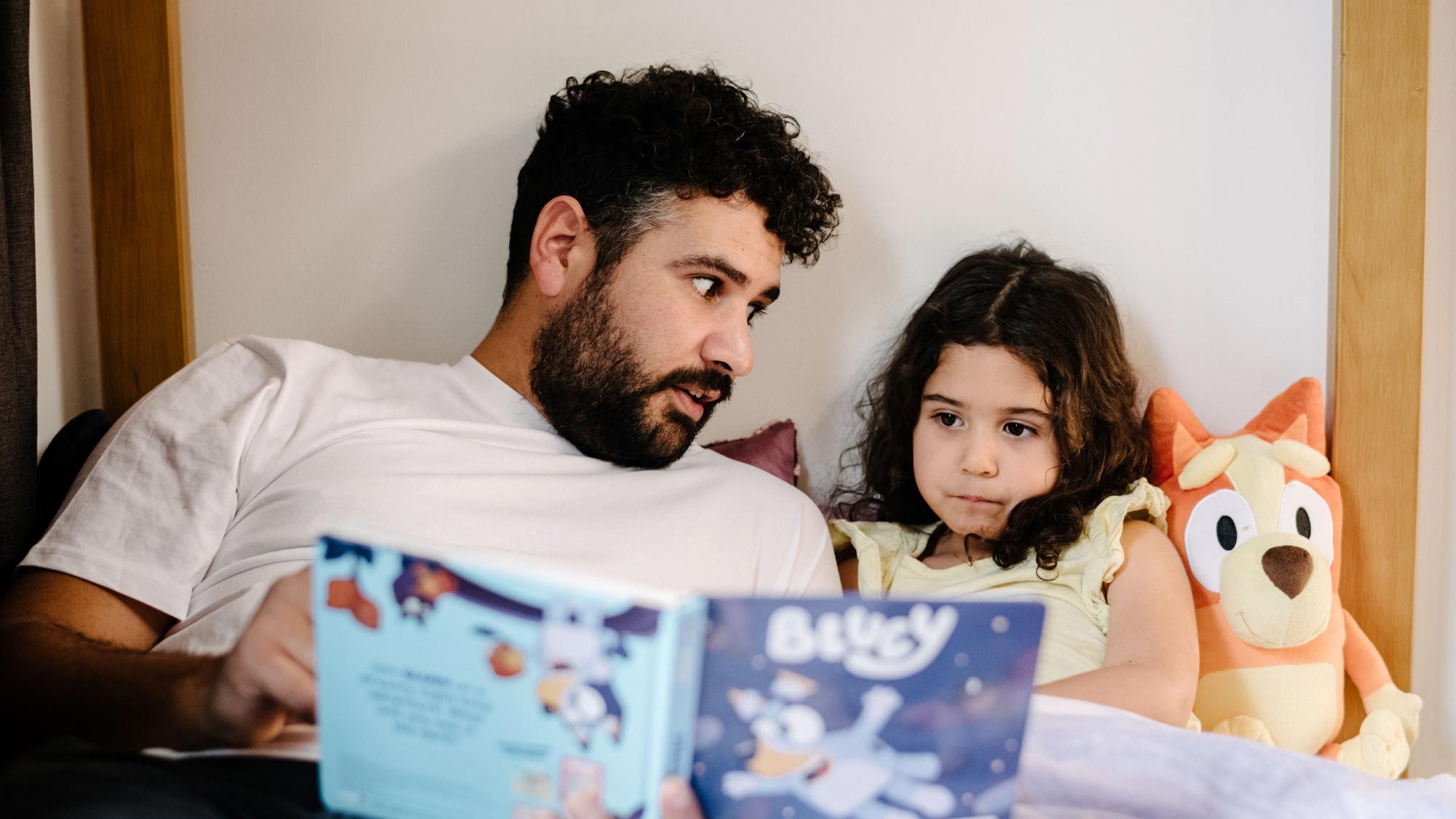 A dad reading a bedtime story to his daughter 