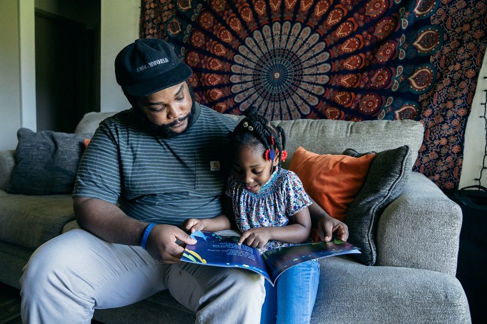 Dad and young daughter spending quality time together reading a book 
