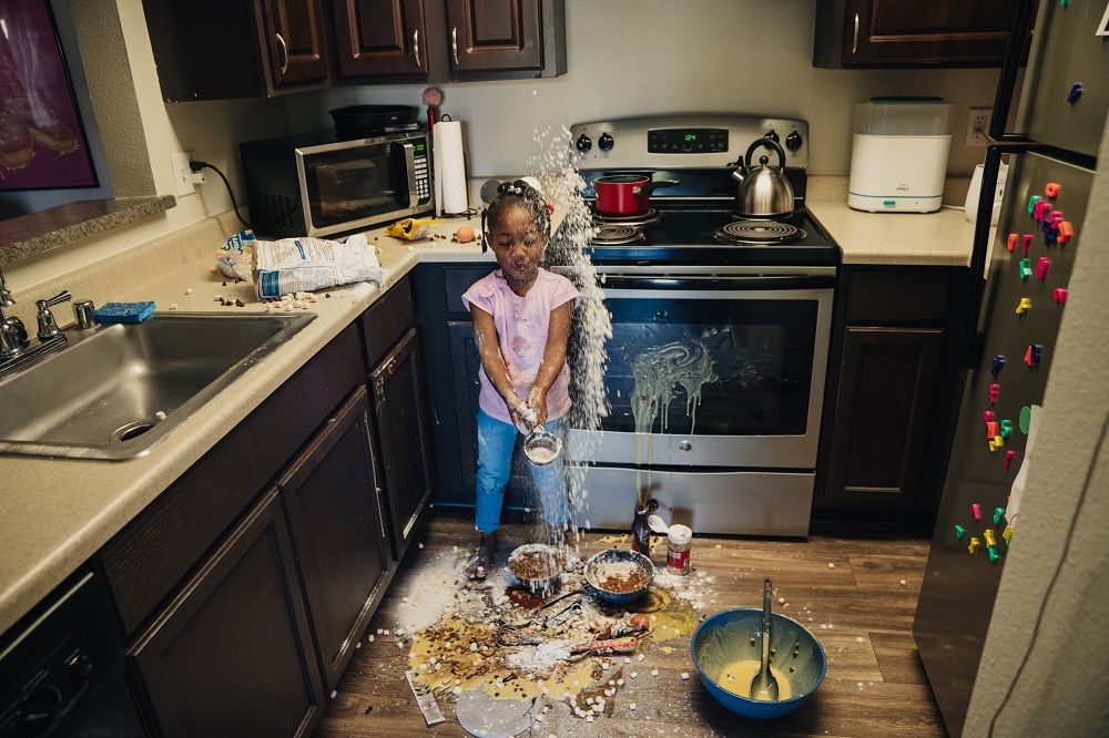 Young girl misbehaving by making a mess in the kitchen 