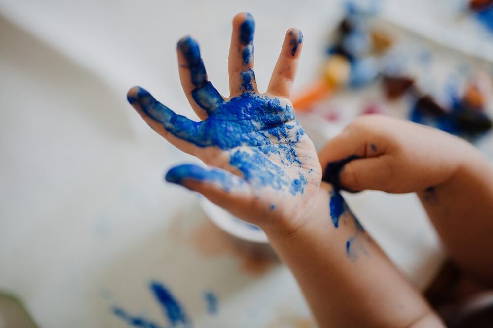 Child's hands covered in blue paint during art time 