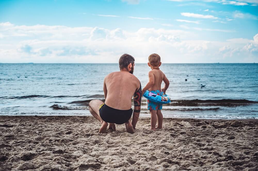 Dad motivating his son to go for a swim at the beach 