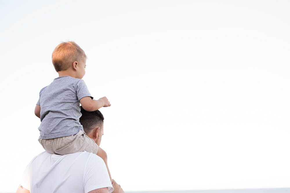 Dad carrying his son on his shoulders practicing positive parenting