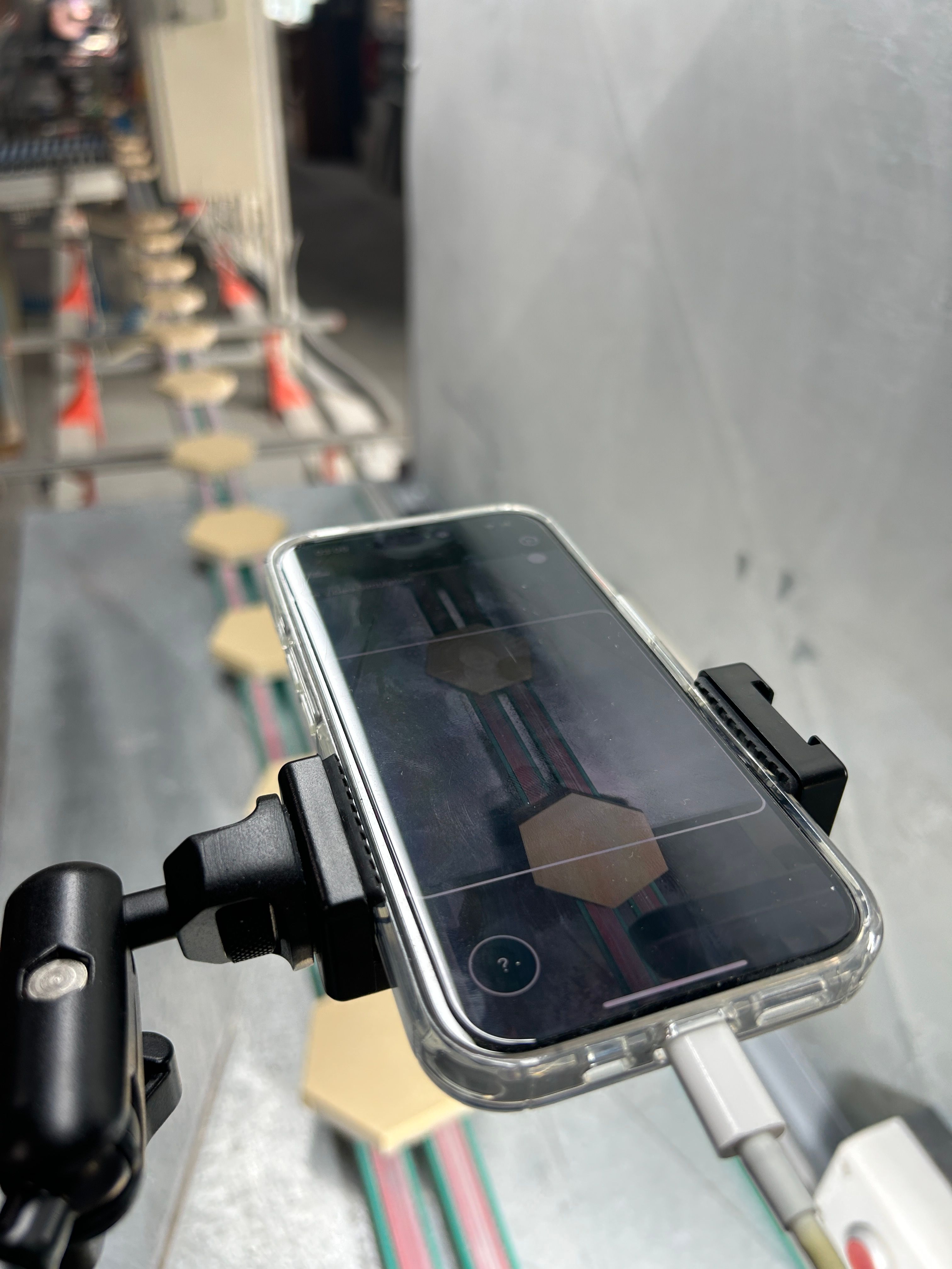 Refurbed iPhone auf einem Enao-Prüfrig vor fertigen Dachziegeln auf der Linie