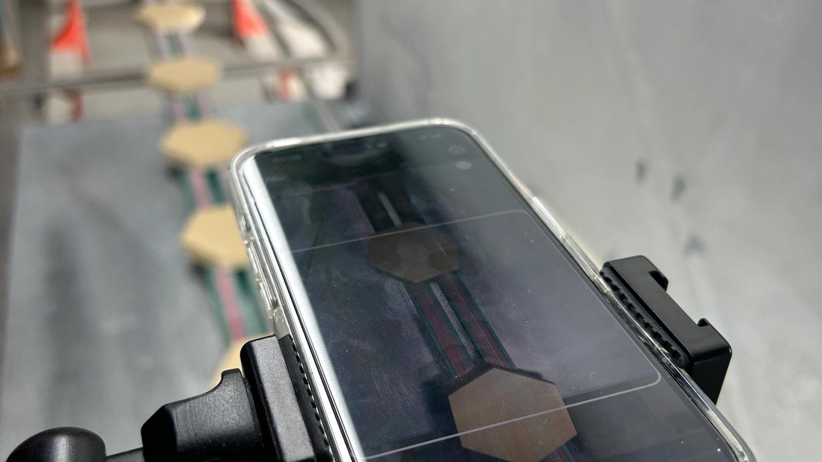 Refurbed iPhone auf einem Enao-Prüfrig vor fertigen Dachziegeln auf der Linie